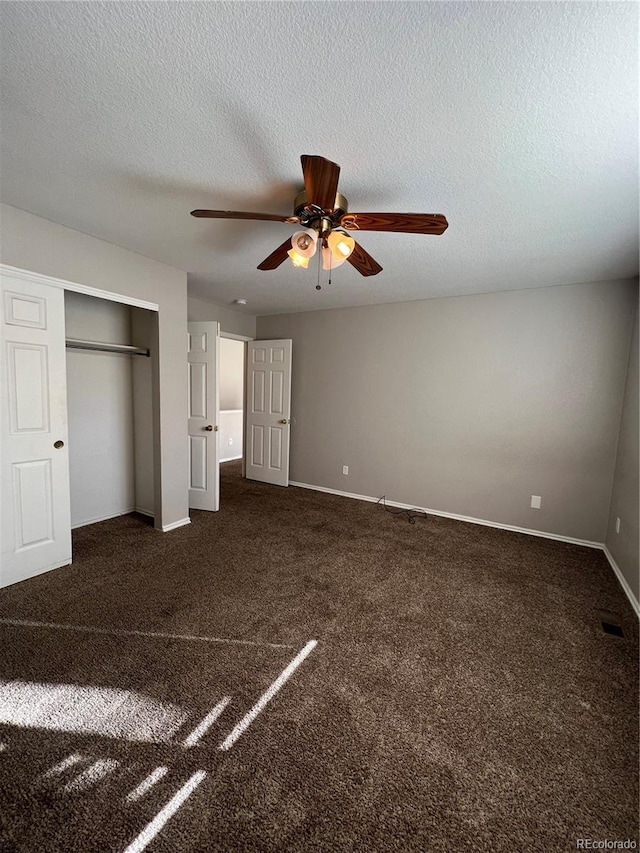 unfurnished bedroom with ceiling fan, a closet, dark carpet, and a textured ceiling