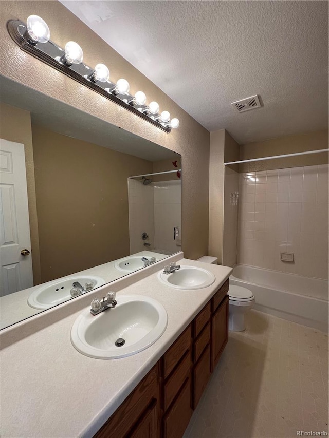 full bathroom with tiled shower / bath combo, toilet, a textured ceiling, and vanity