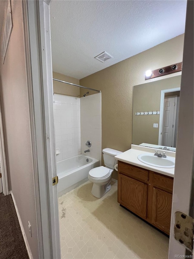 full bathroom featuring a textured ceiling, vanity, toilet, and tiled shower / bath