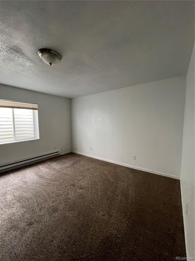 empty room with a textured ceiling, dark carpet, and baseboard heating