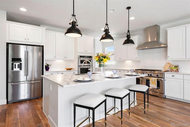 4142 Saltbrush Ct, Loveland, CO 80538 - kitchen featuring premium appliances, wall chimney range hood, recessed lighting, dark wood-style floors, and a center island with sink