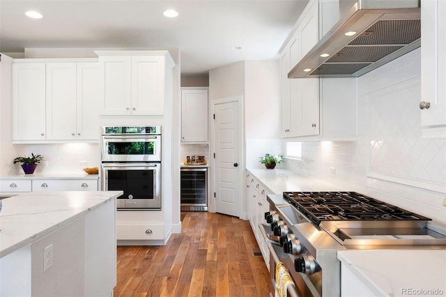 4142 Saltbrush Ct, Loveland, CO 80538 - kitchen with custom range hood, appliances with stainless steel finishes, wine cooler, light wood-type flooring, and recessed lighting