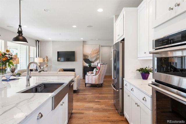 4142 Saltbrush Ct, Loveland, CO 80538 - kitchen featuring stainless steel appliances, white cabinets, light wood-type flooring, light stone counters, and recessed lighting