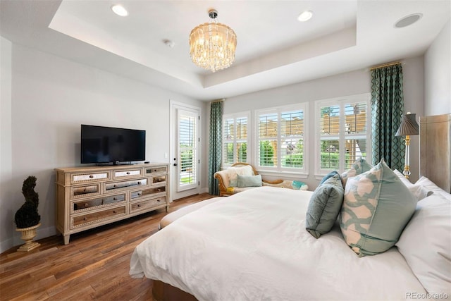 4142 Saltbrush Ct, Loveland, CO 80538 - bedroom featuring a tray ceiling, wood finished floors, access to exterior, a chandelier, and multiple windows