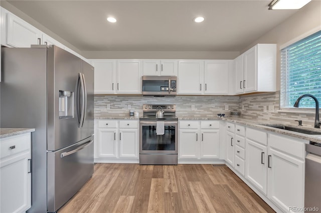 9884 Sydney Ln, Highlands Ranch, CO 80130 - kitchen with appliances with stainless steel finishes, a sink, white cabinetry, tasteful backsplash, and recessed lighting