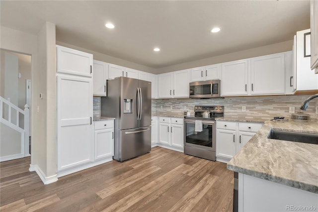 9884 Sydney Ln, Highlands Ranch, CO 80130 - kitchen featuring stainless steel appliances, a sink, light stone counters, light wood-style floors, and recessed lighting