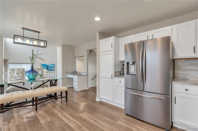 9884 Sydney Ln, Highlands Ranch, CO 80130 - kitchen featuring stainless steel fridge, white cabinetry, light wood-style floors, light stone counters, and recessed lighting