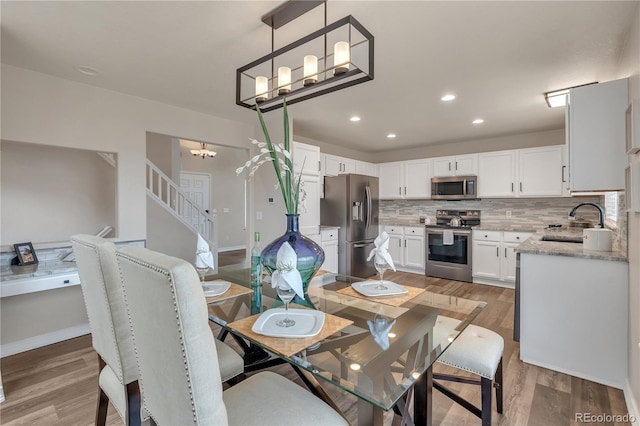 9884 Sydney Ln, Highlands Ranch, CO 80130 - dining area with light wood-style floors, a chandelier, recessed lighting, and baseboards