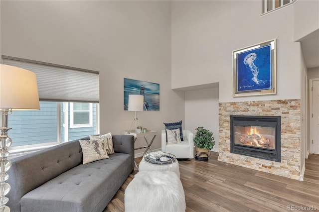 9884 Sydney Ln, Highlands Ranch, CO 80130 - living area featuring wood finished floors, a glass covered fireplace, a towering ceiling, and baseboards