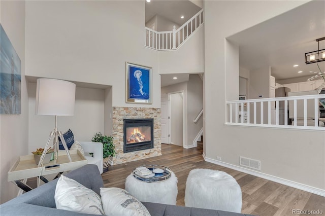 9884 Sydney Ln, Highlands Ranch, CO 80130 - living area with wood finished floors, a towering ceiling, a glass covered fireplace, stairs, and baseboards