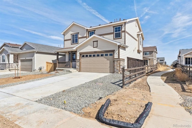 view of front of property featuring concrete driveway, fence, stone siding, and a residential view