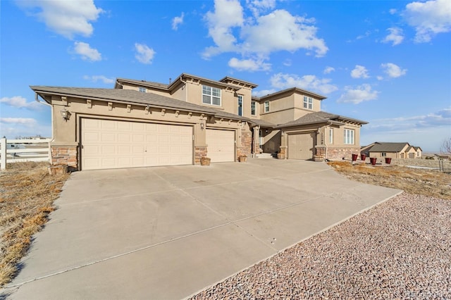 prairie-style home featuring stone siding, stucco siding, driveway, and fence