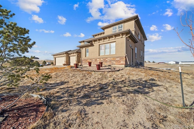 view of front of house featuring stucco siding, stone siding, and an attached garage