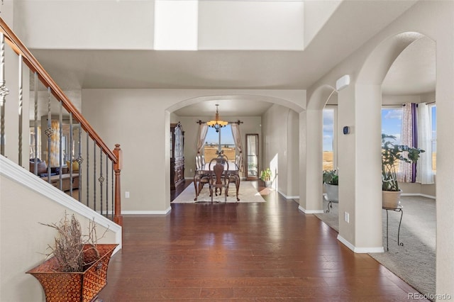 foyer with stairs, hardwood / wood-style flooring, baseboards, and arched walkways