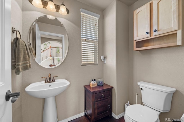 bathroom with a sink, baseboards, toilet, and wood finished floors