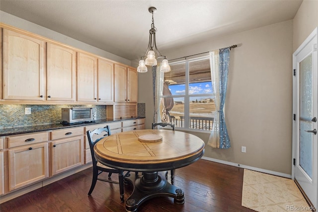 dining room featuring baseboards, dark wood-style floors, and a toaster