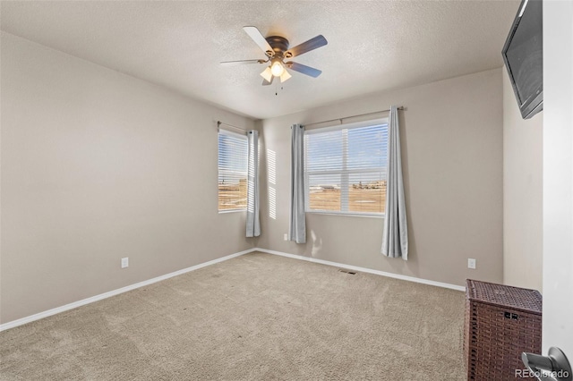 carpeted empty room featuring a textured ceiling, baseboards, and ceiling fan