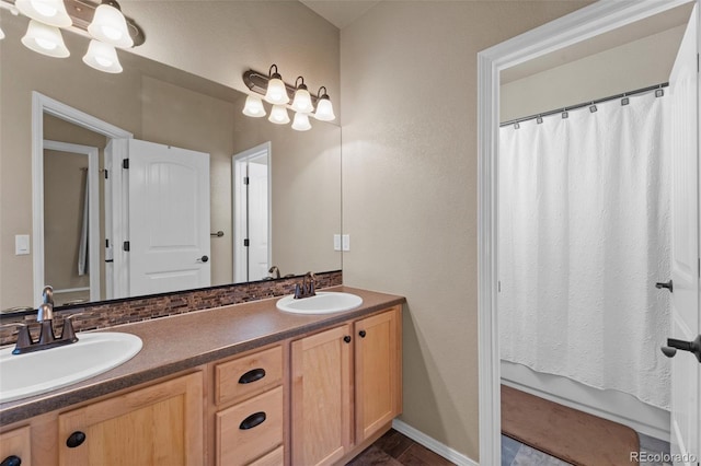 full bathroom featuring a shower with shower curtain, double vanity, baseboards, and a sink