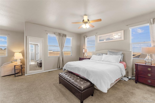 carpeted bedroom featuring multiple windows, baseboards, and ceiling fan