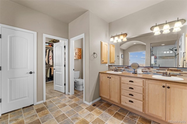 full bathroom with double vanity, a stall shower, stone finish flooring, and a sink