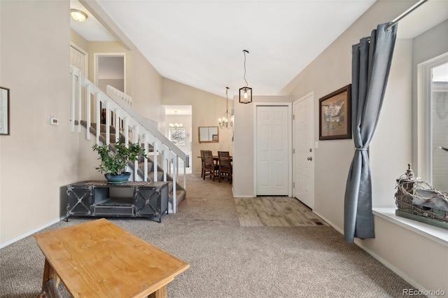 carpeted entrance foyer featuring baseboards, vaulted ceiling, stairway, and a notable chandelier