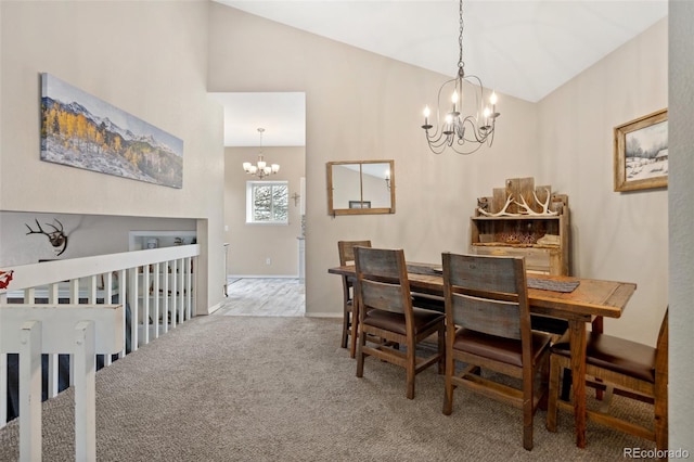 carpeted dining room featuring an inviting chandelier and high vaulted ceiling