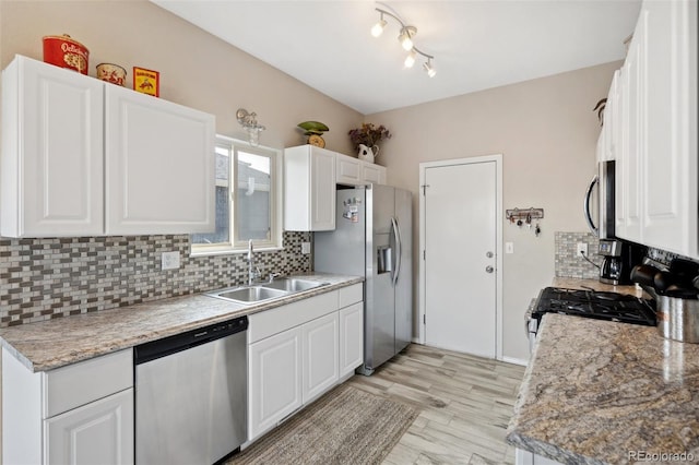 kitchen with white cabinets, light countertops, stainless steel appliances, tasteful backsplash, and a sink