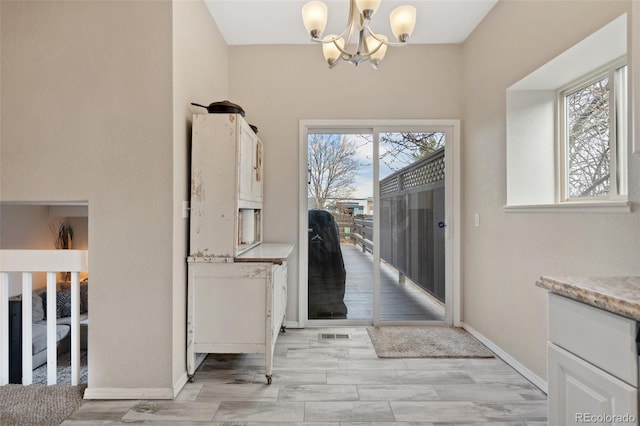 doorway featuring a wealth of natural light, baseboards, and a chandelier