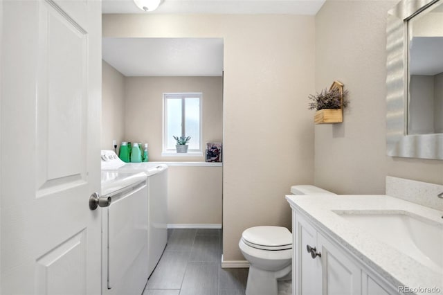bathroom with baseboards, toilet, tile patterned floors, vanity, and washer and dryer