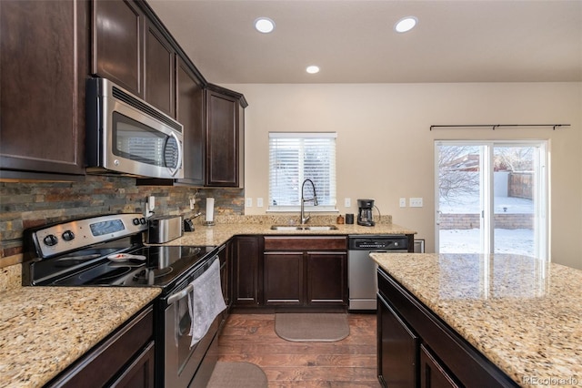 kitchen with backsplash, sink, dark hardwood / wood-style floors, light stone counters, and stainless steel appliances