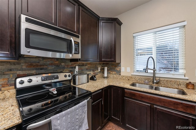 kitchen featuring light stone countertops, tasteful backsplash, dark brown cabinetry, stainless steel appliances, and sink