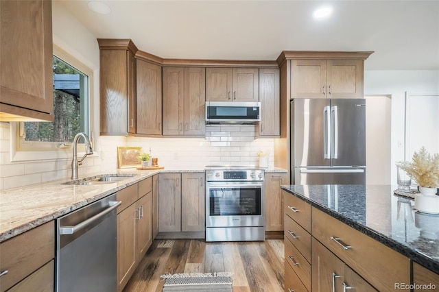 kitchen with stone counters, dark hardwood / wood-style floors, sink, decorative backsplash, and stainless steel appliances