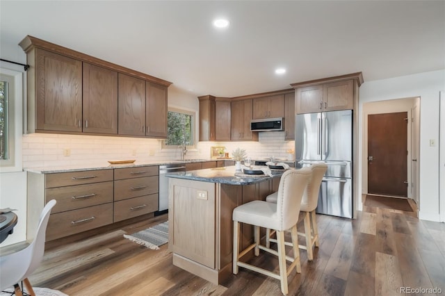 kitchen featuring a kitchen island, tasteful backsplash, dark stone countertops, dark hardwood / wood-style flooring, and stainless steel appliances