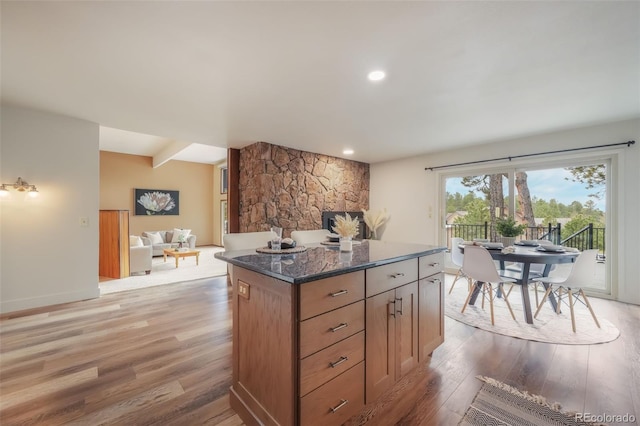 kitchen featuring a kitchen island, light hardwood / wood-style flooring, and dark stone countertops