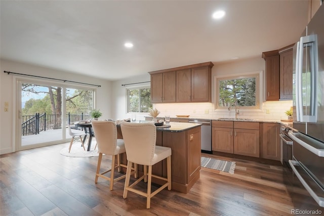 kitchen with dark hardwood / wood-style floors, sink, backsplash, a center island, and stainless steel dishwasher