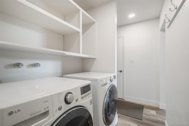 laundry room with washing machine and clothes dryer and light hardwood / wood-style floors