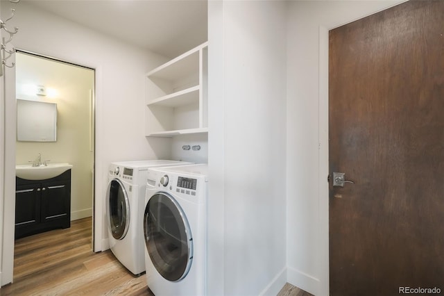 laundry room with sink, washer and dryer, and light wood-type flooring