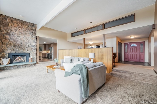 living room featuring beamed ceiling, a fireplace, and carpet floors