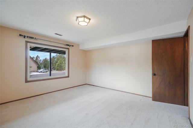 unfurnished room featuring light carpet and a textured ceiling