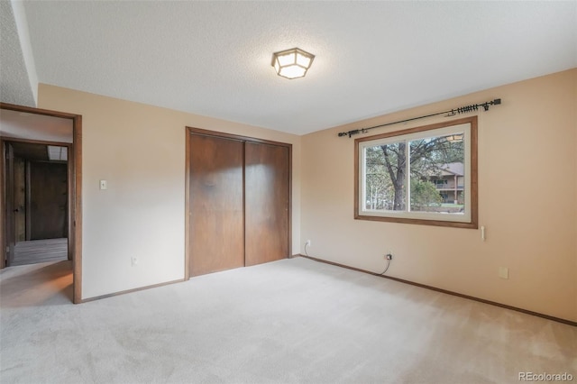 unfurnished bedroom with a closet, light carpet, and a textured ceiling