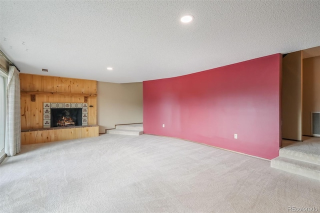 unfurnished living room featuring light colored carpet, a fireplace, and a textured ceiling