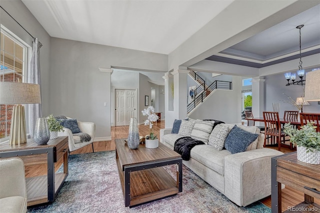 581 Stonemont Dr, Castle Pines, CO 80108 - living room featuring decorative columns, wood finished floors, stairway, a chandelier, and baseboards