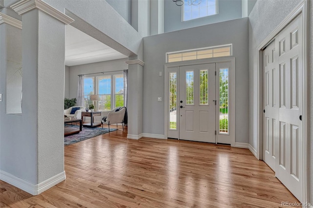 581 Stonemont Dr, Castle Pines, CO 80108 - foyer entrance with wood finished floors, baseboards, a towering ceiling, and decorative columns