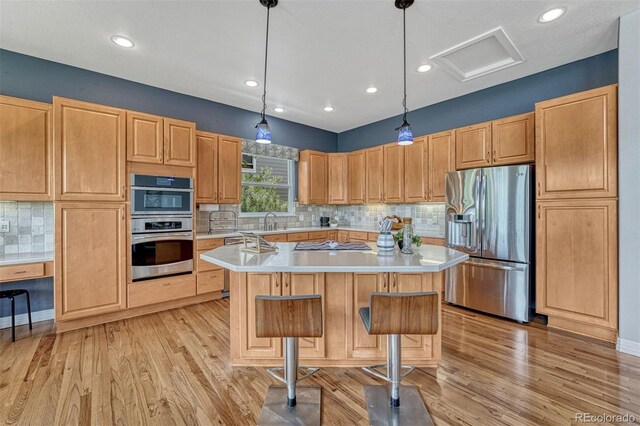 581 Stonemont Dr, Castle Pines, CO 80108 - kitchen with stainless steel appliances, light countertops, light wood-style floors, a center island, and recessed lighting