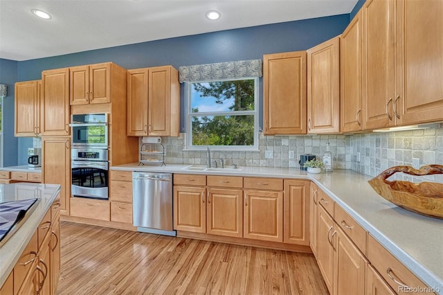 581 Stonemont Dr, Castle Pines, CO 80108 - kitchen with appliances with stainless steel finishes, a sink, light wood-style floors, tasteful backsplash, and recessed lighting