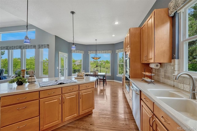 581 Stonemont Dr, Castle Pines, CO 80108 - kitchen with a sink, stainless steel dishwasher, wood finished floors, black electric cooktop, and light countertops