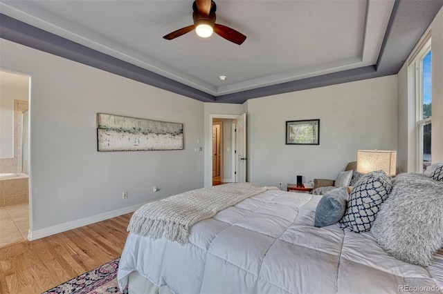581 Stonemont Dr, Castle Pines, CO 80108 - bedroom with a tray ceiling, light wood-type flooring, baseboards, ceiling fan, and ensuite bathroom