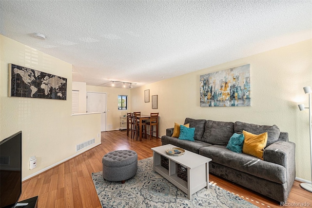 2 Acoma St Unit 11, Denver, CO 80223 - living area with wood finished floors, a textured ceiling, baseboards, and track lighting