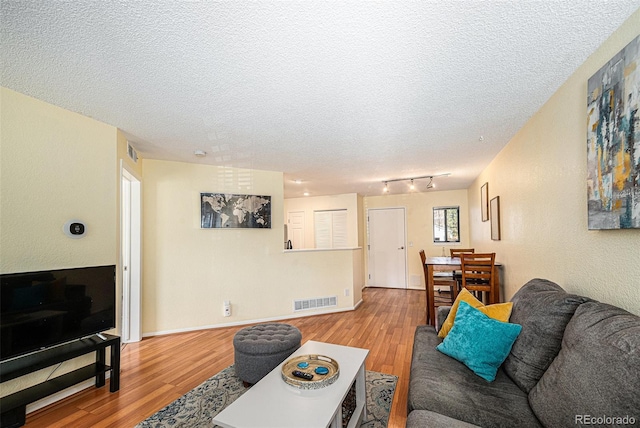 2 Acoma St Unit 11, Denver, CO 80223 - living room featuring wood finished floors, a textured ceiling, rail lighting, and baseboards
