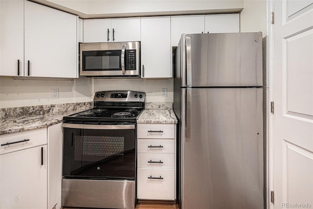 2 Acoma St Unit 11, Denver, CO 80223 - kitchen featuring stainless steel appliances, white cabinetry, and light stone counters